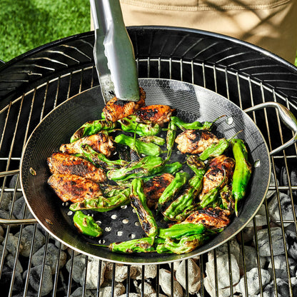 Chicken wings and green peppers being sauted in the HexClad 12&quot Hybrid BBQ Grill Pan on top of a grill