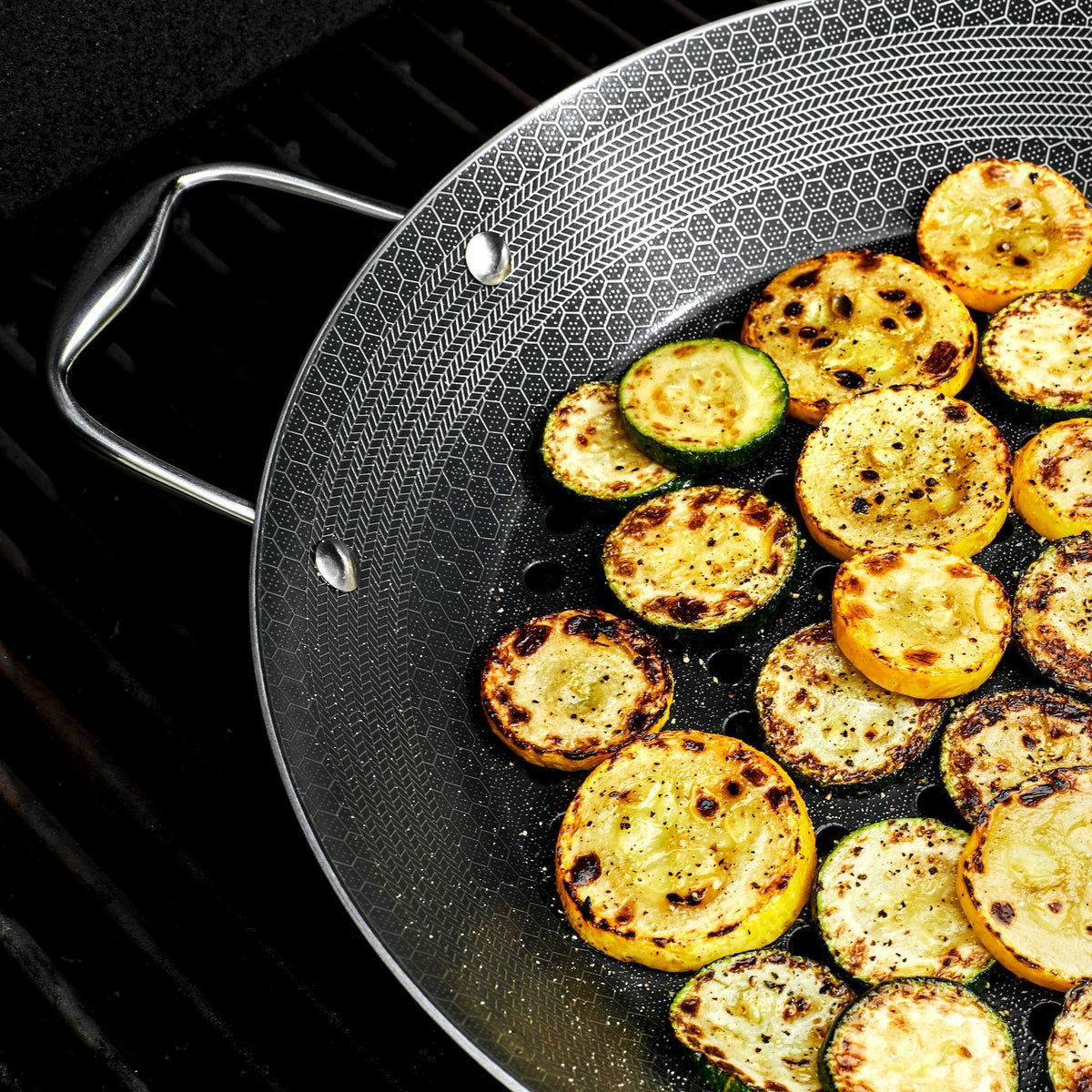 Pieces of squash and zucchini being cooked in the HexClad 12&quot Hybrid BBQ Grill Pan